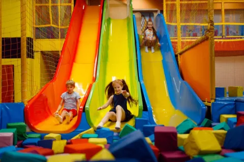 Kids enjoying indoor jumping and sliding.